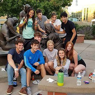 护理 students pose for the camera by the Jesus Among Us statue