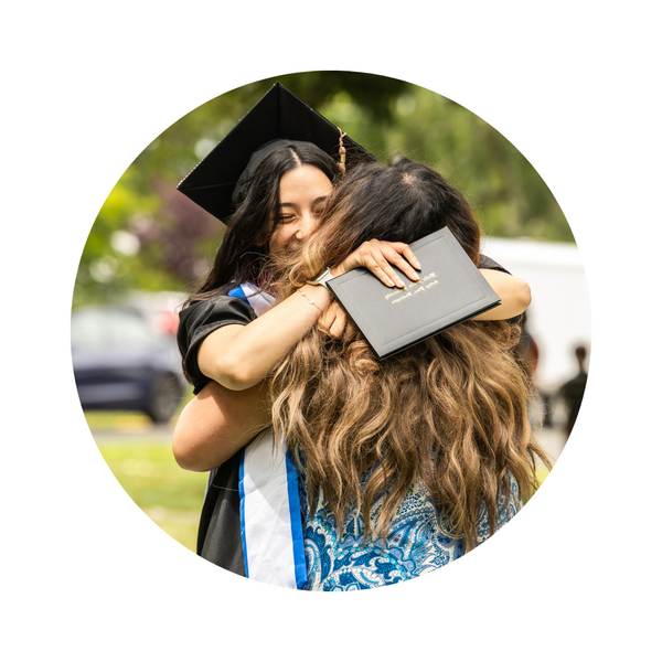 Happy student at graduation hugging someone.